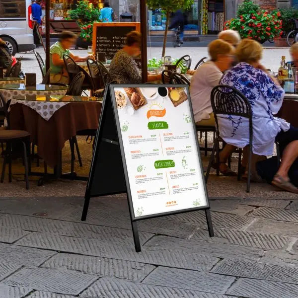Chevalet stop trottoir noir en aluminium avec affiche menu installé devant un restaurant