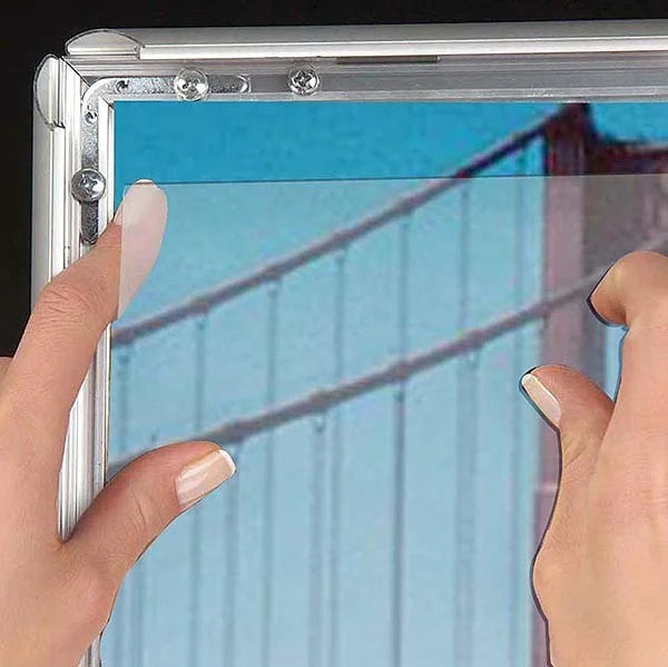 Insertion d’une affiche dans un cadre clic-clac A2 aluminium argent avec système d’ouverture rapide pour changement de visuel