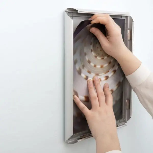 Photo contexte - Installation d’une affiche dans un cadre clic-clac en aluminium argenté pour affichage mural