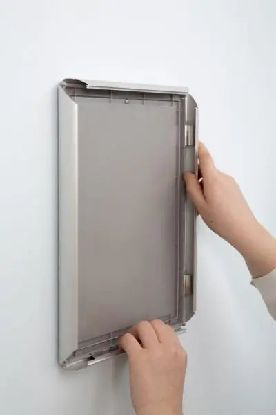 Photo contexte - Installation d’une affiche dans un cadre clic-clac en aluminium argenté pour affichage mural