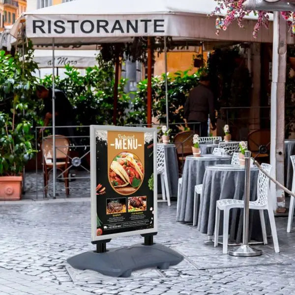 Panneau stop trottoir aluminium noir avec socle lestable installé devant un café