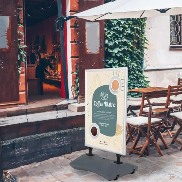 Panneau stop trottoir aluminium noir avec socle lestable installé devant un café