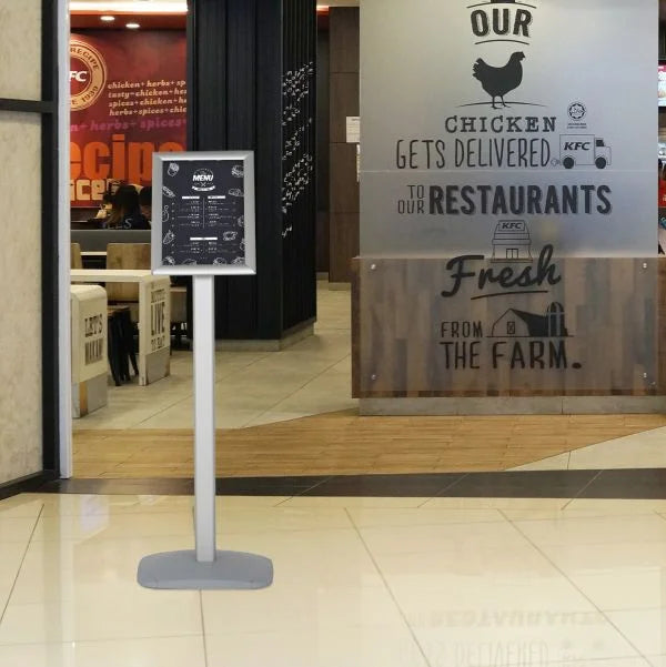 Porte affiche A4 aluminium sur pied avec cadre clic-clac installé devant un restaurant